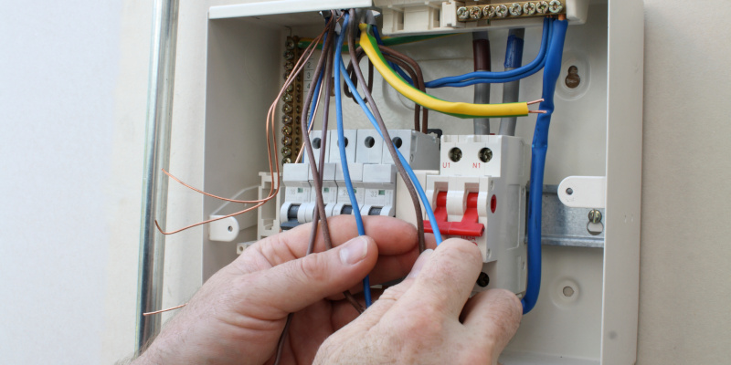 Electrician connecting up a fuse box. Electrician installing a new fuse box